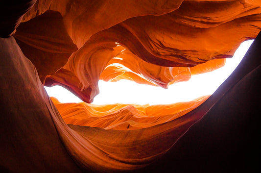 Photographie prise par l’artiste Yorick Serriere depuis l’intérieur Antelope Canyon en Arizona aux États-Unis. Le premier plan est sombre et le centre lumineux. Les couleurs de la roche sont ocres.
