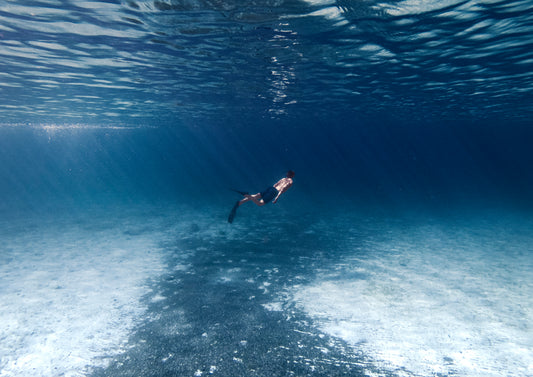 Photographie d’un homme en maillot de bain bleu avc masque et tuba sous l’eau faites en Corse en France par l’artiste Yorick Serriere. Le nageur est au centre de la photographie qui est d’un bleu profond.