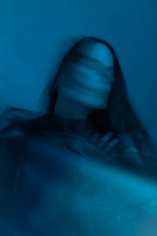 Photographie flou d’une femme aux cheveux très longs. Cette photo prise par l’artiste Alice Sevilla est toute en nuances de bleus.