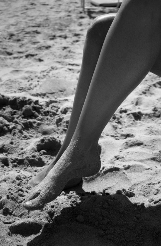 Photographie de jambes de femme sur la plage en noir et blanc. Plage de Tavernes en Espagne. Photo prise par Alice Sevilla.